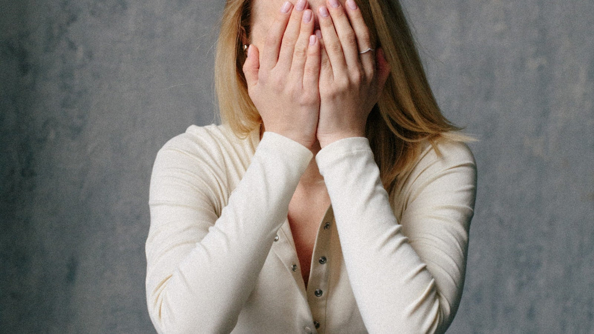 A woman with her hands over her face, taking a moment