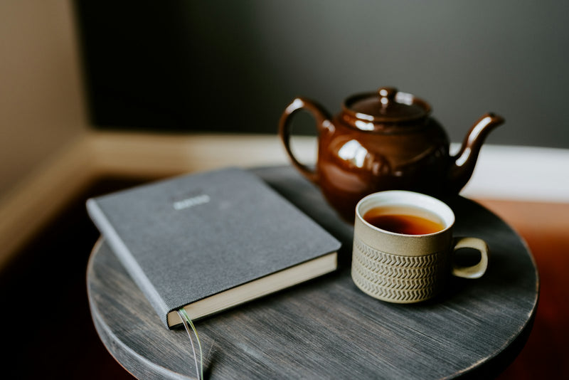 A cup of tea and a closed book on a small table
