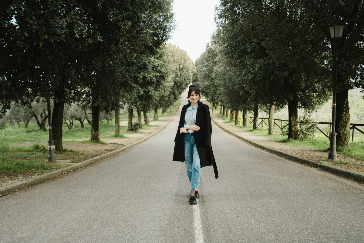 A woman walking alone along a quiet tree lined road
