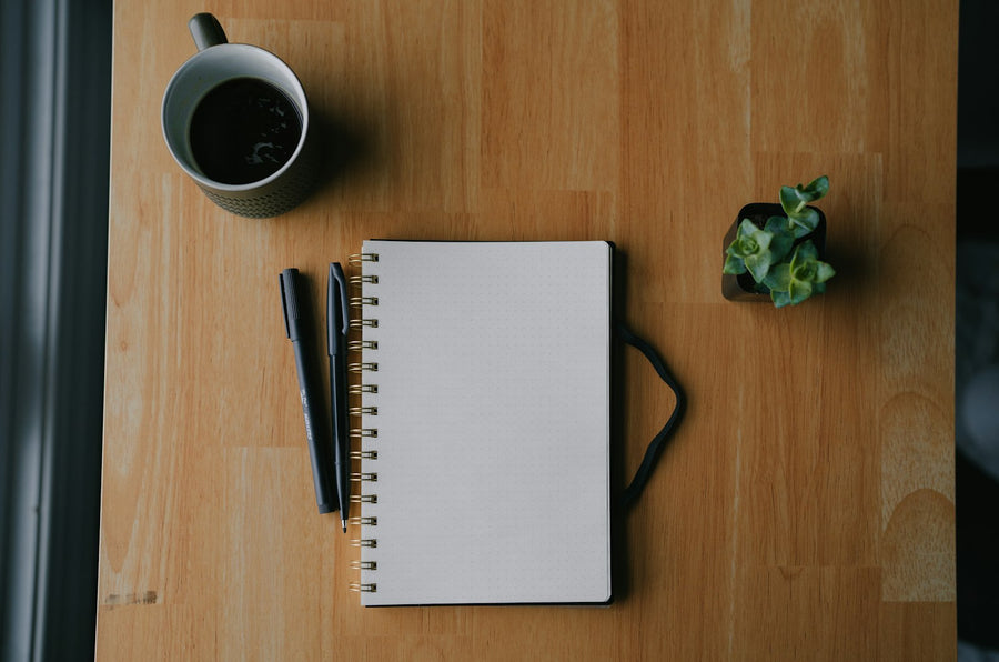 An open notebook and a cup of coffee on a wooden table