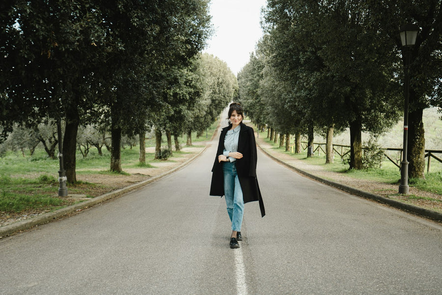 A woman walking alone along a quiet tree lined road